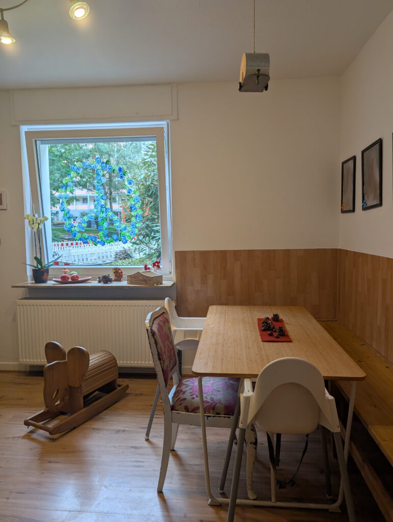 Gemütlicher Essbereich einer Kindertagespflege mit Holztisch, kindgerechten Hochstühlen und einem Schaukel-Elefant aus Holz